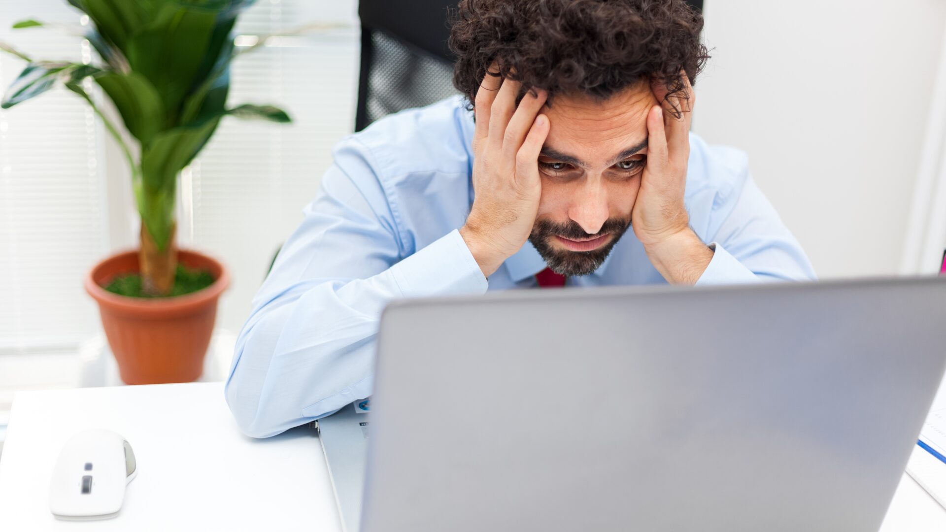 A man not looking happy a his laptop.