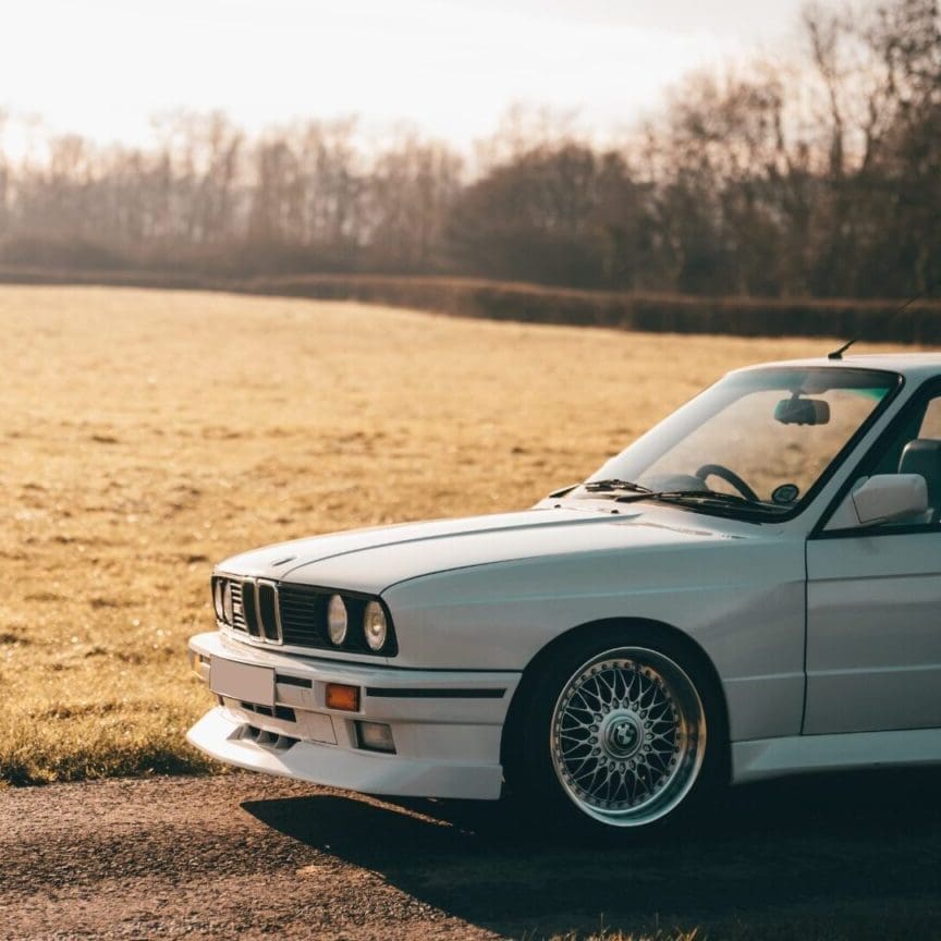 The front end of a white 1989 BMW E30 3.